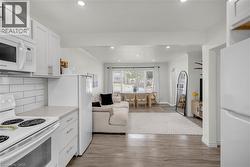 Open-concept living space featuring wood-finish flooring, white cabinetry, integrated microwave, and recessed lighting - 