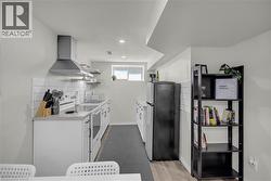 Contemporary kitchen featuring white cabinetry, subway tile backsplash, a stainless steel range hood, and a built-in electric range - 