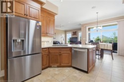 Kitchen featuring wood cabinetry, stainless steel appliances, a tile backsplash, and a light-toned countertop - 