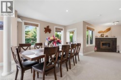 Recessed lighting, light-toned carpeting, multiple windows, fireplace with dark tile surround, and an exterior door with glass panels - 