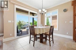 Sliding glass doors opening to an outdoor deck, large window with blinds, tile flooring, and a chandelier light fixture - 