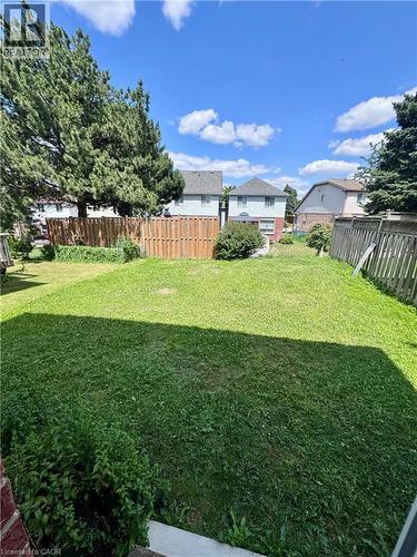 Expansive backyard with a lush lawn, featuring a wood privacy fence and mature trees - 452 Beaumont Crescent, Kitchener, ON 