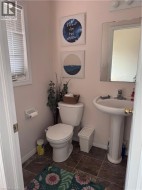 Bathroom featuring a pedestal sink, wall-mounted mirror, and tile flooring - 