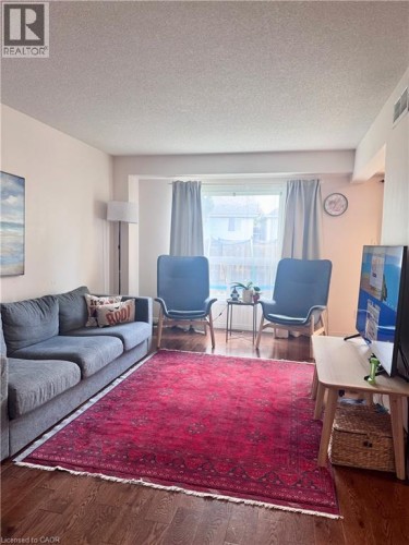 Living area featuring wood-finish flooring, light-toned walls, and a window with natural light - 452 Beaumont Crescent, Kitchener, ON 