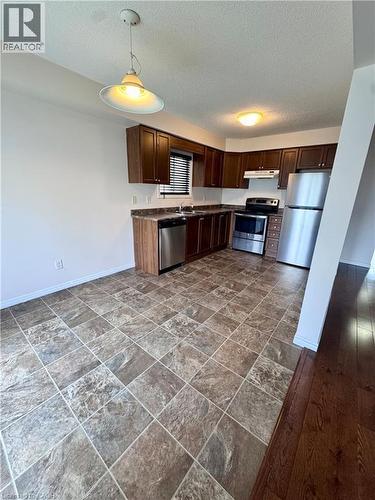 Kitchen featuring dark wood cabinetry, stainless steel appliances, and a tiled floor - 452 Beaumont Crescent, Kitchener, ON 