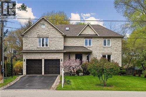 Stone facade residence featuring a two-car garage, mature landscaping, and an asphalt driveway - 1541 Garnet Avenue, Mississauga, ON 