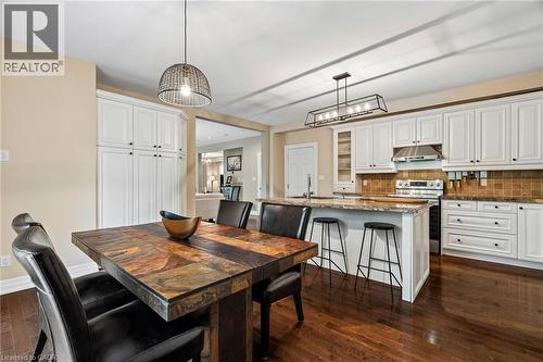 Kitchen featuring white cabinetry, stainless steel appliances, a tile backsplash, and an island with bar seating - 1541 Garnet Avenue, Mississauga, ON 