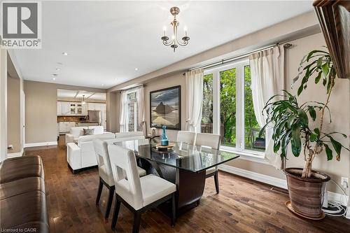 Dining area with wood-finish flooring, a contemporary chandelier, and large windows with white trim - 1541 Garnet Avenue, Mississauga, ON 