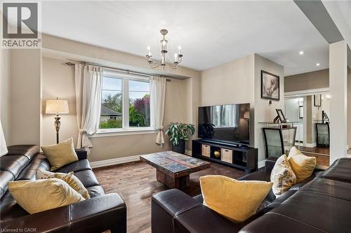 Living area featuring wood-finish flooring, a double-paned window, and a chandelier with candelabra bulbs - 1541 Garnet Avenue, Mississauga, ON 