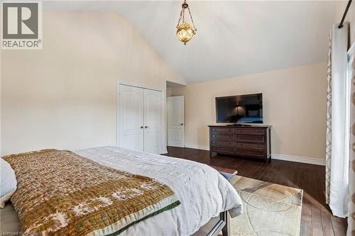 Vaulted ceiling with an ornate pendant light fixture, wood-finish flooring, white baseboards, and double closet doors - 1541 Garnet Avenue, Mississauga, ON 