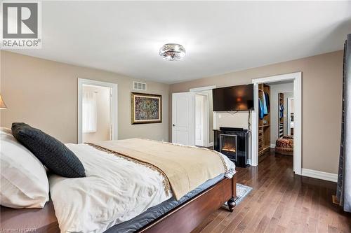 Hardwood flooring throughout featuring a ceiling-mounted light fixture, recessed wall niche with built-in electric fireplace, and an expansive walk-in closet with custom shelving - 1541 Garnet Avenue, Mississauga, ON 