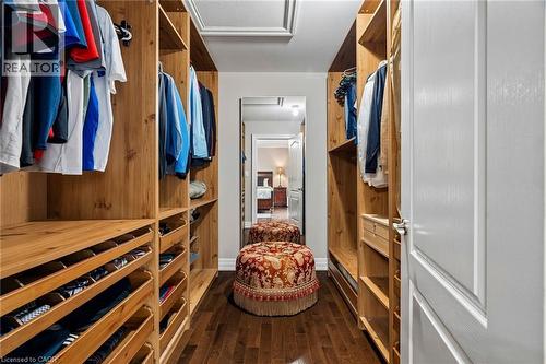 Walk-in closet featuring extensive built-in wood-finish shelving and hanging storage, deep wood-finish drawers, and rich wood-finish flooring - 1541 Garnet Avenue, Mississauga, ON 