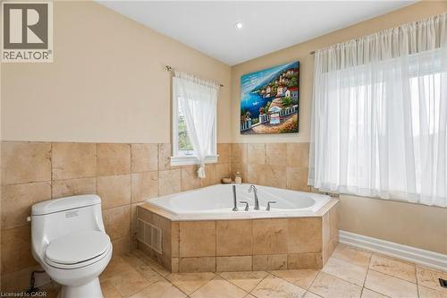 Corner soaking tub set within a tiled surround, complemented by full-height wall tiling and matching floor tiles - 1541 Garnet Avenue, Mississauga, ON 