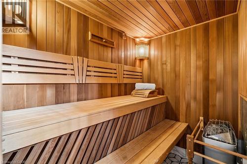 Custom sauna featuring natural wood paneling, slatted benches, ambient wall sconces, and a built-in heating unit with a protective grate - 1541 Garnet Avenue, Mississauga, ON 
