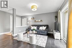Spacious living area featuring wood-finish flooring, light gray walls, a sliding glass door, and a semi-recessed ceiling light fixture - 