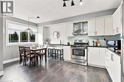 Kitchen with white cabinetry, stainless steel appliances, dark countertops, and wood-finish flooring - 