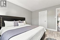 Spacious room featuring wood-finish flooring, a paneled door, and recessed lighting - 