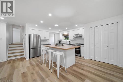 Modern kitchen featuring an island with a wood-finish countertop, stainless steel appliances, white cabinetry, and recessed lighting - 2306 Devon Road, Oakville, ON 