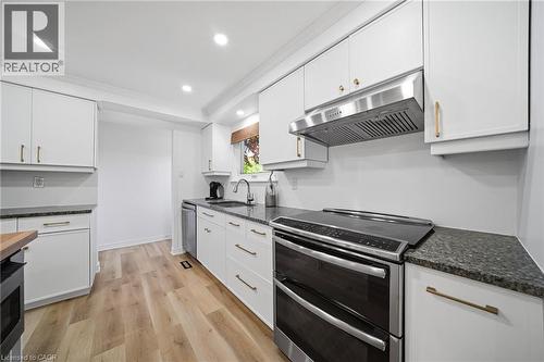 Kitchen featuring white cabinetry with gold-toned hardware, granite countertops, and vinyl flooring - 2306 Devon Road, Oakville, ON 