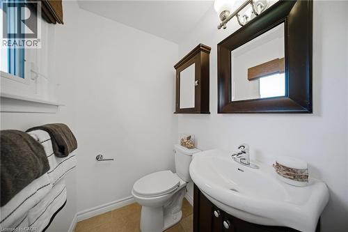 Bathroom featuring a window, built-in medicine cabinet, ceramic toilet, vanity with integrated sink, and polished chrome faucet - 2306 Devon Road, Oakville, ON 