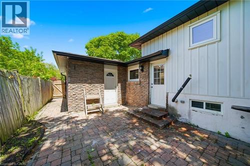 Exterior brick paver patio with a stone facade accent wall, white board and batten siding, and two entry doors - 2306 Devon Road, Oakville, ON 