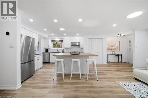 Modern kitchen featuring white cabinetry, stainless steel appliances, and a central island with a wood-finish countertop - 2306 Devon Road, Oakville, ON 