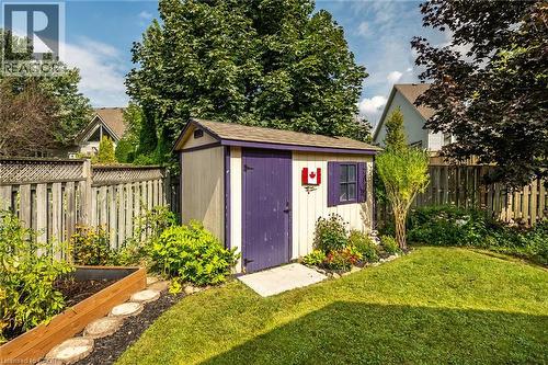 Fenced backyard with a storage shed, lawn area, and raised garden bed - 159 Thoroughbred Boulevard, Ancaster, ON 