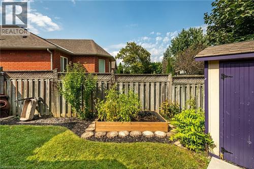 Fenced backyard featuring a raised garden bed, an exterior shed, and mature landscaping - 159 Thoroughbred Boulevard, Ancaster, ON 