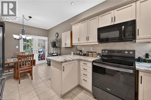 Kitchen featuring light cabinetry, solid surface countertops, tile backsplash, and tile flooring - 159 Thoroughbred Boulevard, Ancaster, ON 