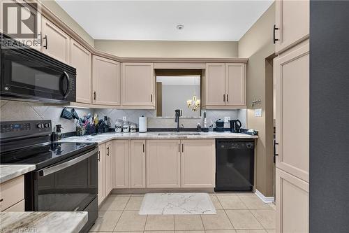 Kitchen with light-toned cabinetry, light-toned countertops, and a tile backsplash - 159 Thoroughbred Boulevard, Ancaster, ON 