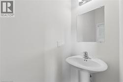 Pedestal sink with chrome-finish faucet, rectangular wall-mounted mirror, and overhead light fixture - 