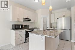 Kitchen featuring a center island, integrated sink, stainless steel appliances, upper and lower cabinetry, and tiled flooring - 