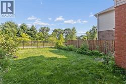 Expansive green space featuring a wood fence, iron fence, and mature trees - 