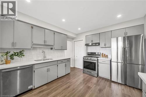 Kitchen featuring wood-finish flooring, recessed lighting, gray cabinetry, stainless steel appliances, and a white subway tile backsplash - 284 Cedar Crescent, Cambridge, ON 