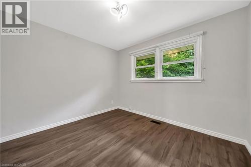 Wood-finish flooring, white trim, light gray walls, white window frames, and a ceiling-mounted light fixture - 284 Cedar Crescent, Cambridge, ON 