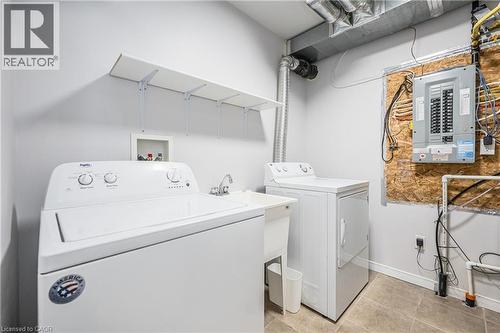 Laundry area featuring a utility sink, tiled flooring, and overhead shelving - 224 Jessica Crescent Unit# B, Kitchener, ON 