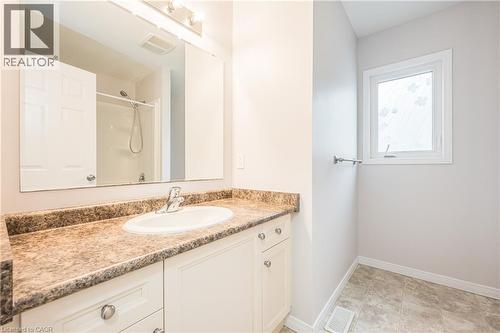 Vanity with a laminate countertop and integrated sink, chrome faucet, wall-mounted mirror, and tile flooring - 224 Jessica Crescent Unit# B, Kitchener, ON 