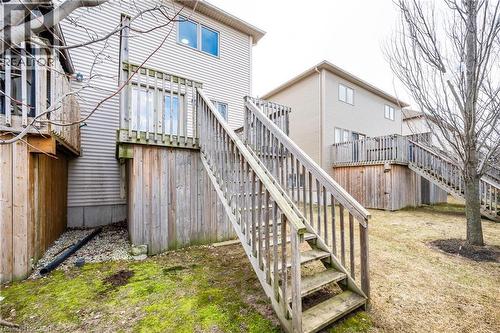 Rear exterior featuring light-toned siding, a wood deck with railings, and an exterior staircase - 224 Jessica Crescent Unit# B, Kitchener, ON 