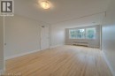Hardwood flooring, painted walls, three-panel window, baseboard heater, and flush-mount lighting fixture - 141 Chapel Street, Kitchener, ON 