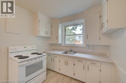 White cabinetry, light-toned countertops, wood-finish flooring, and a stainless steel sink - 141 Chapel Street, Kitchener, ON 