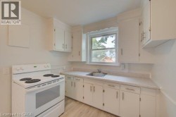 White cabinetry, light-toned countertops, wood-finish flooring, and a stainless steel sink - 