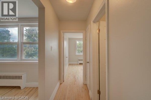 Light wood-finish flooring throughout, white trim, and a flush mount ceiling light - 141 Chapel Street, Kitchener, ON 