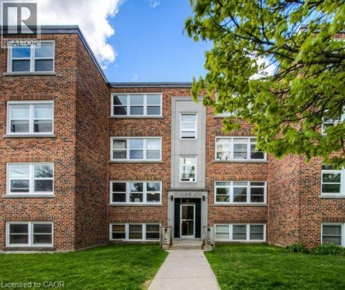 Brick exterior with multiple windows, a central entrance, and a concrete pathway - 141 Chapel Street, Kitchener, ON 