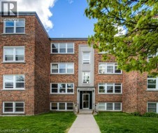 Brick exterior with multiple windows, a central entrance, and a concrete pathway - 