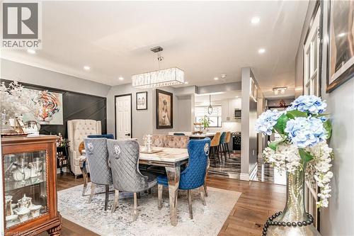 Open-concept dining area featuring wood-finish flooring, recessed lighting, and a linear chandelier - 52 Charters Road, Brampton, ON 