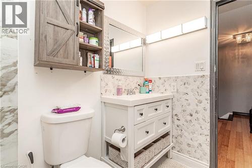 White vanity with integrated sink, patterned tile backsplash, mirrored medicine cabinet, and wall-mounted light fixture - 52 Charters Road, Brampton, ON 