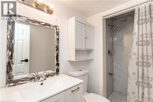 Vanity with an integrated rectangular sink, wall-mounted storage cabinet, and a shower with tile surround - 52 Charters Road, Brampton, ON 
