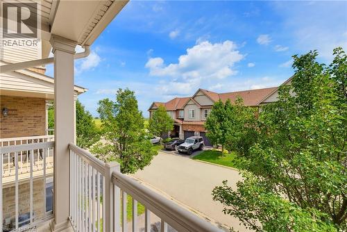Balcony with white railings, brick and siding exterior, green trees, and paved street - 541 Winston Road Unit# 50, Grimsby, ON 