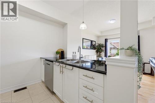 White cabinetry with brushed nickel hardware, black countertop, stainless steel double basin sink, and integrated dishwasher - 541 Winston Road Unit# 50, Grimsby, ON 
