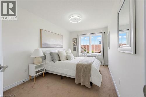 Bright bedroom featuring a large window with grid pattern, neutral-toned walls, and carpet flooring - 541 Winston Road Unit# 50, Grimsby, ON 